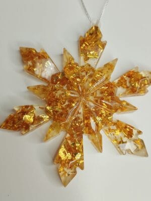 Ornement flocon de neige doré en résine époxy suspendu sur un sapin de Noël décoré