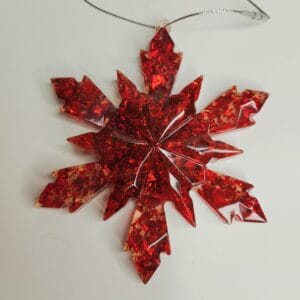 Ornement flocon de neige rouge en résine époxy suspendu sur un sapin décoré pour Noël
