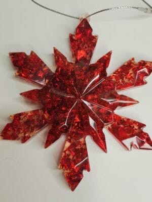 Ornement flocon de neige rouge en résine époxy suspendu sur un sapin décoré pour Noël