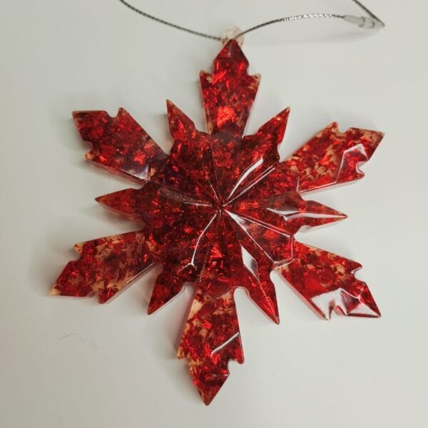 Ornement flocon de neige rouge en résine époxy suspendu sur un sapin décoré pour Noël