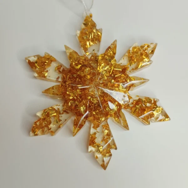 Cette suspension flocon étoile paillettes or est posée sur une table en bois brut, reflétant la douce lueur d'une bougie festive.