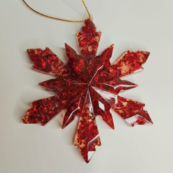 Gros plan sur les paillettes rouges et la transparence de l'ornement flocon de neige