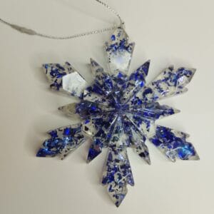 Ornement flocon de neige bleu nuit en résine époxy suspendu sur un sapin de Noël décoré