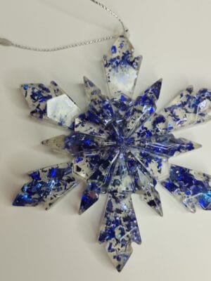 Ornement flocon de neige bleu nuit en résine époxy suspendu sur un sapin de Noël décoré