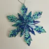 decoration-sapin-flocon-bleu-details Gros plan sur l'ornement géométrique transparent avec paillettes, mettant en valeur la finition parfaitement lisse et les arêtes douces réalisées à la main par l'atelier Pamkycréa.