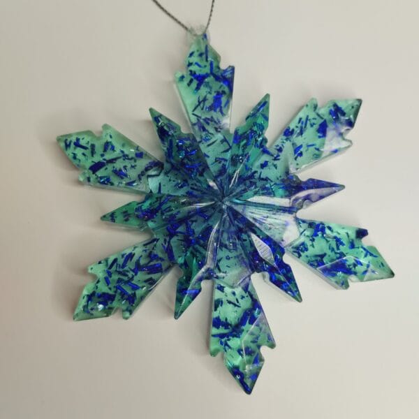 Gros plan sur les paillettes turquoise et bleu nuit de l'ornement flocon de neige