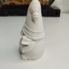 statuette-lutin-noel-personnalisation-peinture Le petit gnome scandinave posé sur un atelier en bois, entouré de pinceaux fins et de petits pots de peinture rouge et verte, prêt à être décoré pour les fêtes de fin d'année.