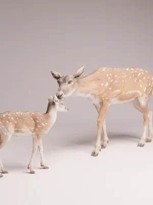 miniature-biche-faon-resine-diorama Vue de face d'une miniature biche et faon pour diorama, montrant le museau du petit touchant celui de sa mère dans une clairière verdoyante.
