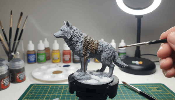 Detailed macro photography of a miniature wolf figurine being painted with a dark brown wash, showing the liquid shade flowing into the fur textures to create depth and realistic shadows, professional lighting.