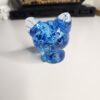 detail-paillettes-chat-bleu-transparent Gros plan sur les paillettes étincelantes à l'intérieur de la statue chat en résine.