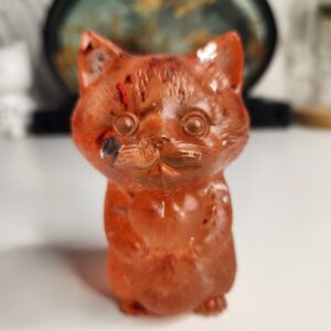 Adorable figurine chat en résine rouge profond tenant un cœur, vue de face.
