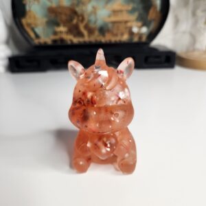 Figurine licorne assise en résine rouge profond avec inclusions de feuilles métalliques brillantes.