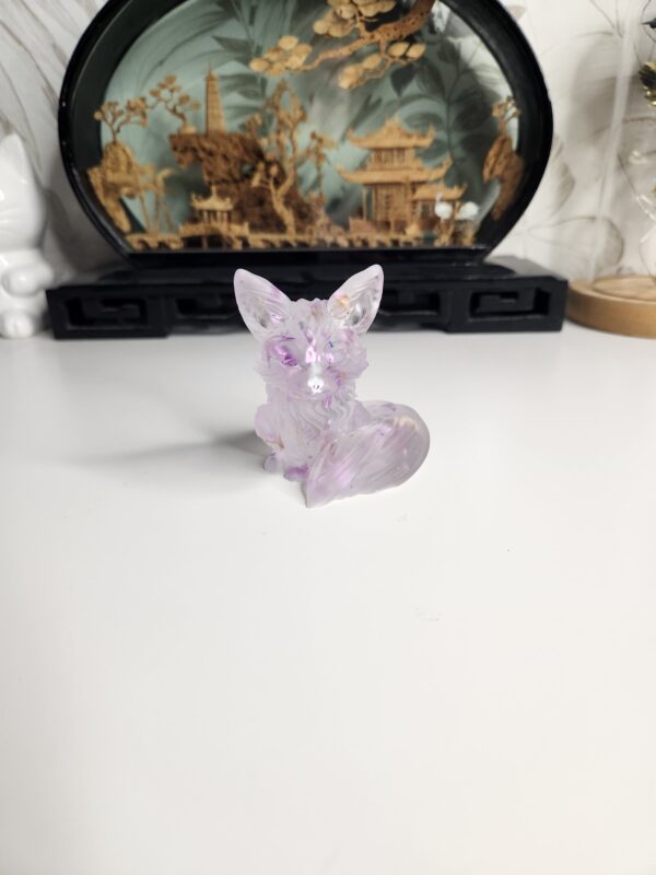 Le petit renard décoratif transparent et violet posé élégamment sur une surface en bois clair.