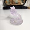 Gros plan sur les fragments de feuille métallique violette scintillante suspendus dans le corps du renard en résine.
