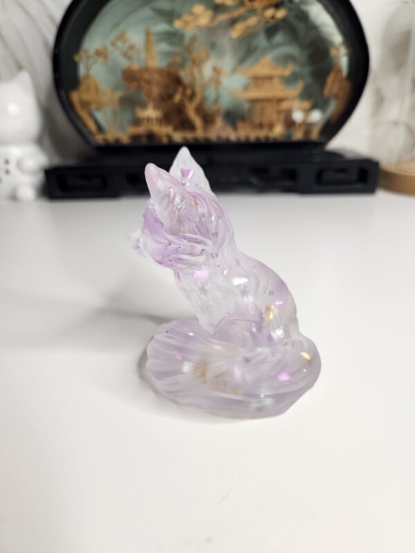 Gros plan sur les fragments de feuille métallique violette scintillante suspendus dans le corps du renard en résine.