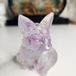 Figurine artisanale de renard assis en résine cristalline avec éclats violets vue de face.