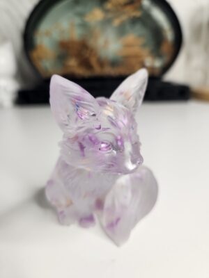 Figurine artisanale de renard assis en résine cristalline avec éclats violets vue de face.