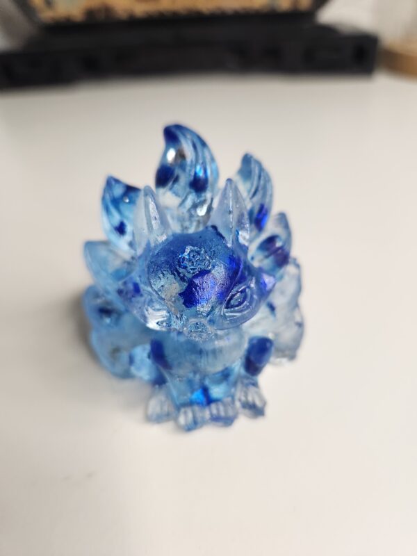 Figurine miniature de Kitsune en résine bleu saphir avec ses neuf queues déployées, vue de face.