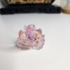 Sculpture de Kitsune de 5 cm captant la lumière sur un bureau, révélant ses inclusions roses et dorées.