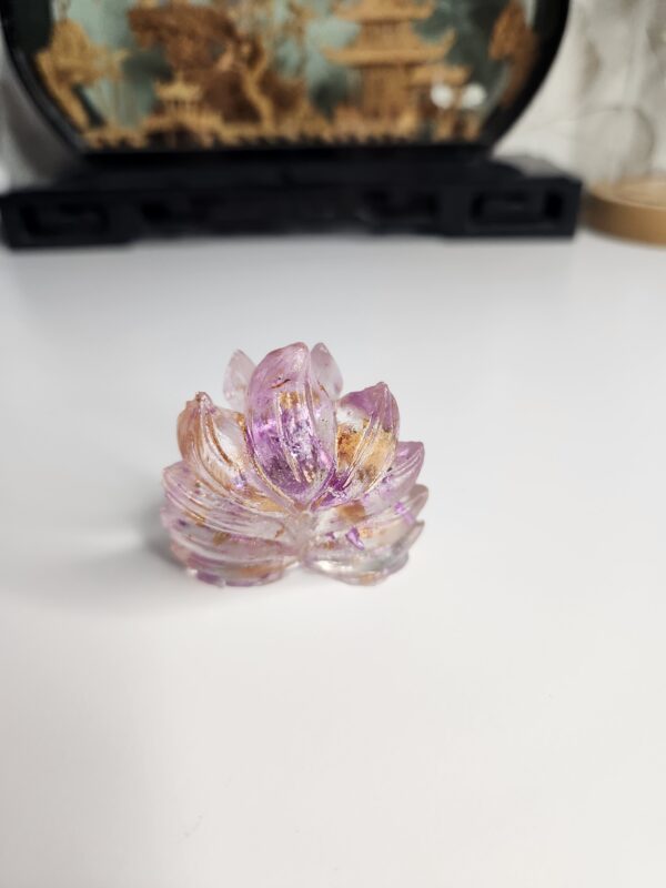 Sculpture de Kitsune de 5 cm captant la lumière sur un bureau, révélant ses inclusions roses et dorées.