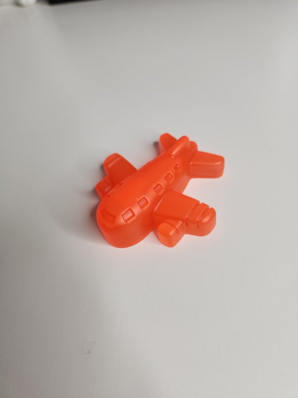 L'avion miniature en résine de 6 cm posé dans la paume d'une main pour montrer sa taille compacte.