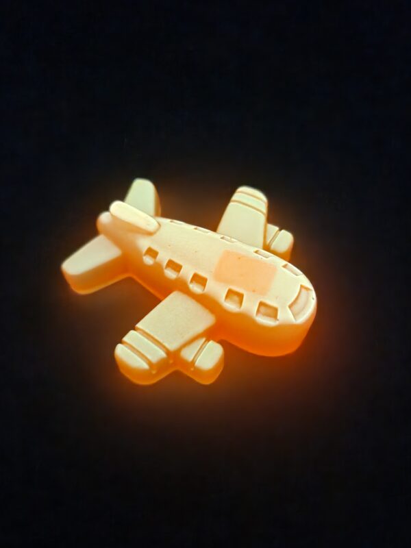Figurine avion miniature monoplan en résine époxy orange vif avec une surface lisse et brillante, vue de jour.