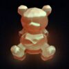Sculpture d'ourson phosphorescent brillant d'une lueur rose dans le noir.
