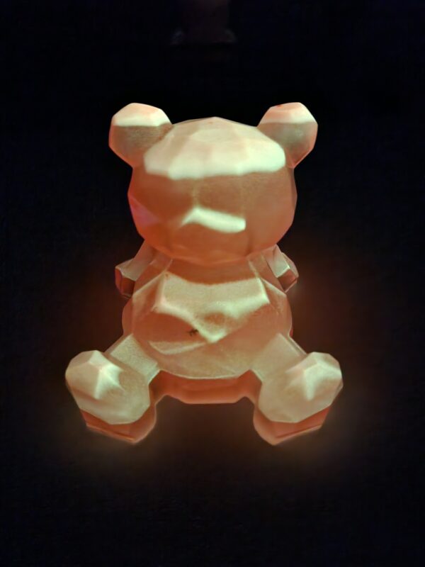 Sculpture d'ourson phosphorescent brillant d'une lueur rose dans le noir.