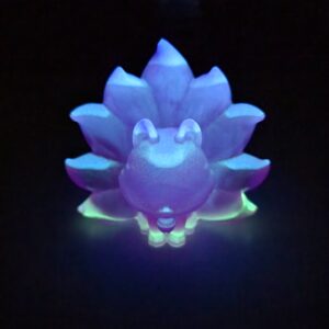 Figurine Kitsune phosphorescente illuminée en bleu et vert dans l'obscurité.