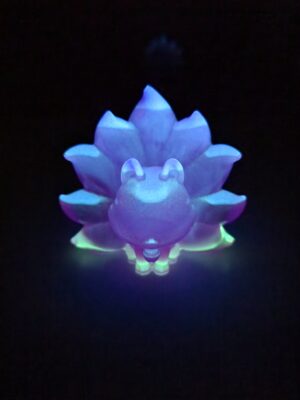 figurine-kitsune-phosphorescente-nuit Figurine Kitsune phosphorescente illuminée en bleu et vert dans l'obscurité.