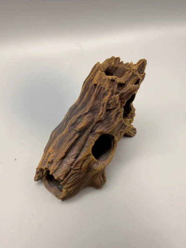 refuge-reptile-aquarium-pla Vue plongeante sur un abri naturel pour reptiles et poissons en forme de rondin creux, montrant les différentes entrées sécurisées pour les petits animaux.