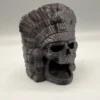 Cachette crâne aztèque pour terrarium installée au milieu de plantes verdoyantes et de substrat, créant un abri naturel et mystique pour les animaux.
