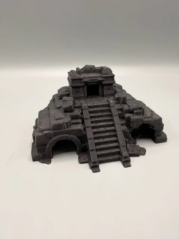 Vue plongeante de profil mettant en valeur les détails de pierre usée et les différentes cavités de la pyramide aztèque miniature.