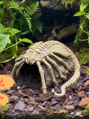 cachette-terrarium-facehugger-pla Vue de face d'une cachette pour terrarium en forme de roche, surmontée d'un parasite extraterrestre avec de longues pattes osseuses.