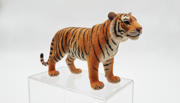 Realistic Schleich tiger figurine with detailed fur texture, standing on a white background, soft studio lighting, high resolution, professional photography.