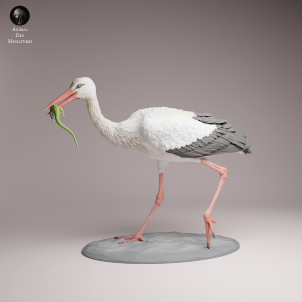 figurine-cigogne-blanche-chasse-lezard Figurine de cigogne blanche à peindre, debout sur un sol sableux, tenant fermement un lézard vert dans son long bec, montrant une posture de chasse dynamique.