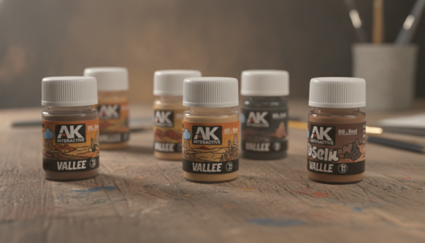Photographie macro de flacons de pigments de modélisme aux teintes terreuses et poussiéreuses, marques AK Interactive et Vallejo sur un établi en bois, éclairage doux de studio.