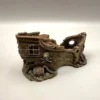 Vue détaillée du socle d'un décor fond marin pour terrarium posé sur un sol texturé, dévoilant un petit coffre aux trésors fermé et entouré de chaînes sculptées à la base de la coque.