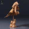 Vue de profil de la chauve-souris vampire suspendue en plein vol grâce à sa tige fixée sur un socle imitant la roche.